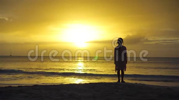 可爱的快乐小女孩在白色海滩日落美丽的夕阳下海岸小女孩的剪影视频的预览图