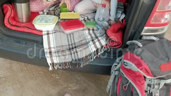 美丽的年轻女子和她的小女儿正坐在一条海边的一辆敞篷汽车的后备箱里视频的预览图