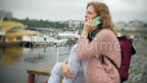 一个女孩在海边使用智能手机游艇在港口航行视频的预览图