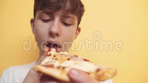 披萨快乐的青少年男孩吃一片披萨的概念十几岁的男孩饿了吃一片披萨慢生活方式运动视频的预览图