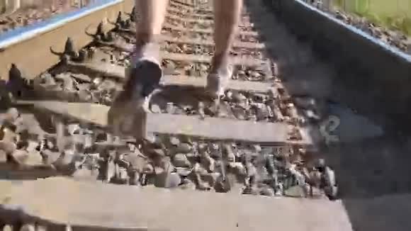 男足在铁轨上的铁轨之间奔跑在铁路枕木上慢跑的跑步者运动腿视频的预览图
