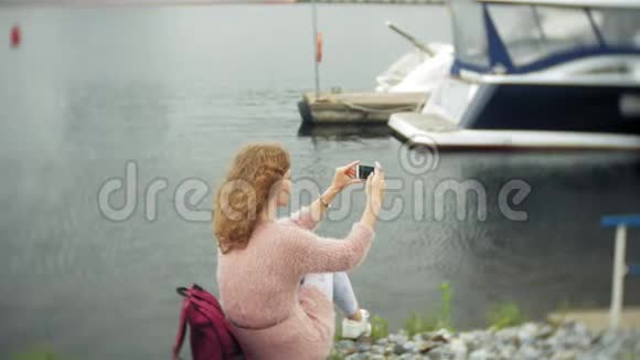 一个女孩在海边使用智能手机游艇在港口航行视频的预览图