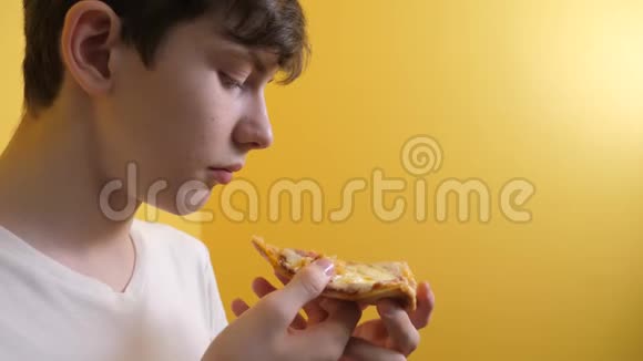 披萨快乐的青少年男孩吃一片披萨的概念十几岁的男孩饿了吃一片比萨饼的生活方式慢动作视频的预览图