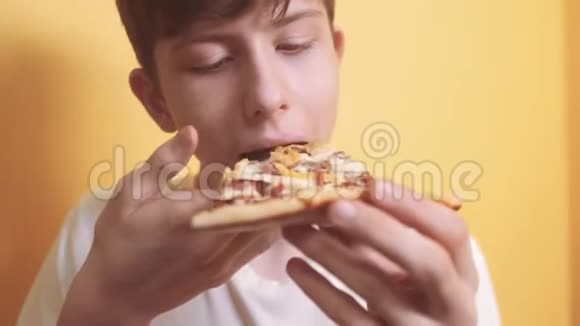 快乐的小男孩吃一片披萨的概念少年男孩饿了吃一片披萨慢动作视频披萨饼视频的预览图
