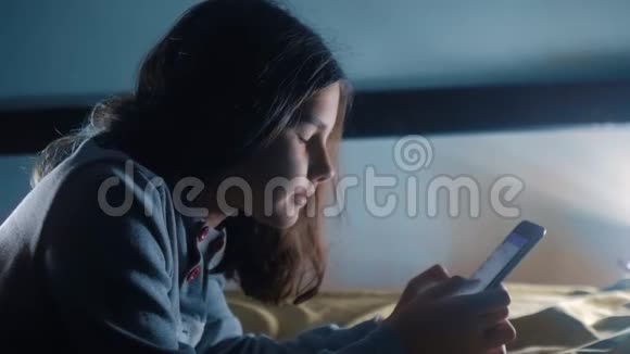 少女和智能手机晚上一个小少女在社交媒体上留言聊天视频的预览图