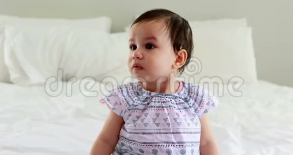可爱的女婴坐在床上视频的预览图