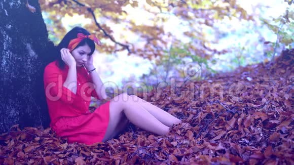一棵树旁的叶子上美丽的黑发女人放松下来视频的预览图