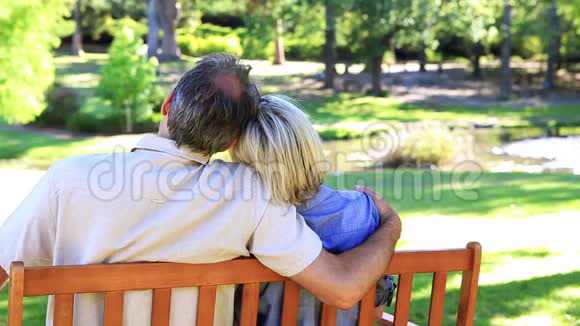 可爱的夫妇坐在公园的长凳上视频的预览图