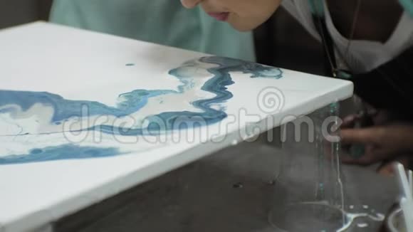 在艺术工作室里的女人用流动的艺术技巧混合颜料和画布视频的预览图