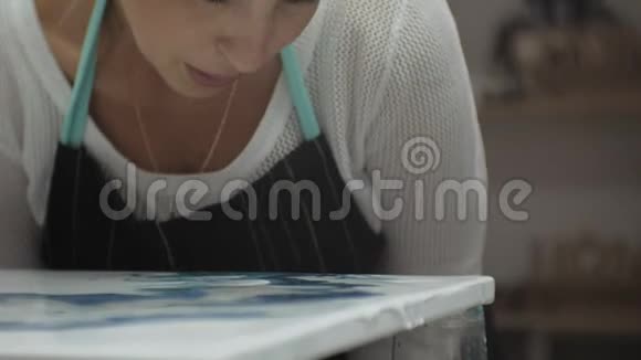 在艺术工作室里的女人用流动的艺术技巧混合颜料和画布视频的预览图
