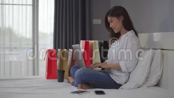 快乐的女人用笔记本电脑上网购物床上有信用卡视频的预览图