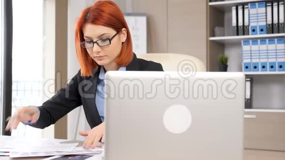 穿着正装的现代女商人在办公桌前工作视频的预览图