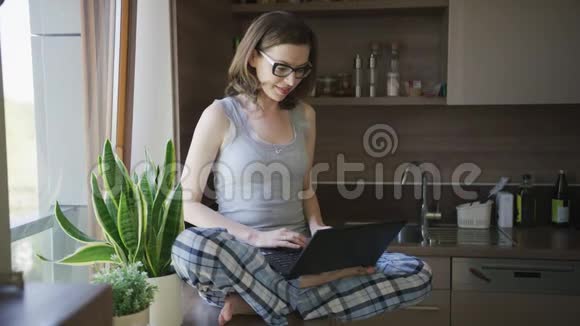 坐在桌子上的年轻女人用笔记本电脑视频的预览图