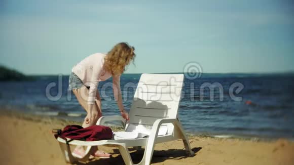 年轻女孩躺在海边沙滩上的躺椅上晒太阳视频的预览图