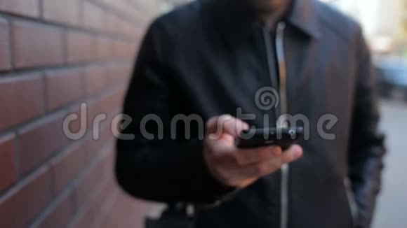那个孤独的年轻人在城市的砖墙附近打电话视频的预览图