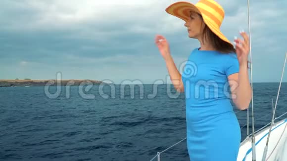 戴着黄色帽子的女人和穿着蓝色衣服的女孩在海洋的夏季在游艇上休息视频的预览图