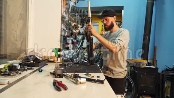 一个留着胡子的男子自行车技工在他的车间里组装了一辆山地自行车视频的预览图