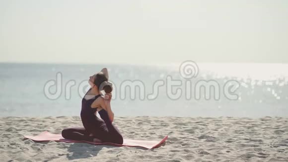 阳光明媚的一天年轻漂亮的女人在海滩上练习瑜伽健康的积极生活方式视频的预览图