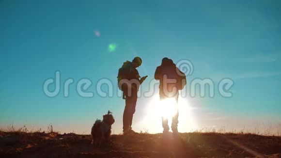 团队合作两名游客徒步旅行男人和狗带着背包在日落时去徒步旅行慢动作录像旅行和徒步旅行者视频的预览图