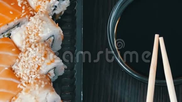 时尚的寿司放在黑色的木制背景上旁边是酱油和中国竹签各种寿司卷视频的预览图