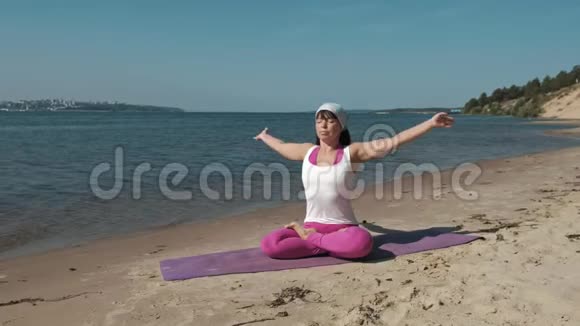 退休老妇人在海滩上做瑜伽视频的预览图