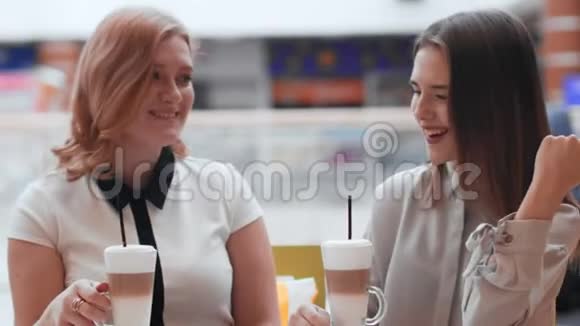两个年轻的女人坐在咖啡馆里聊天喝咖啡视频的预览图