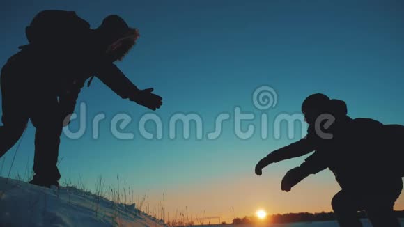 团队合作商务旅行剪影概念两个徒步旅行者冬季雪游客登山到山顶视频的预览图