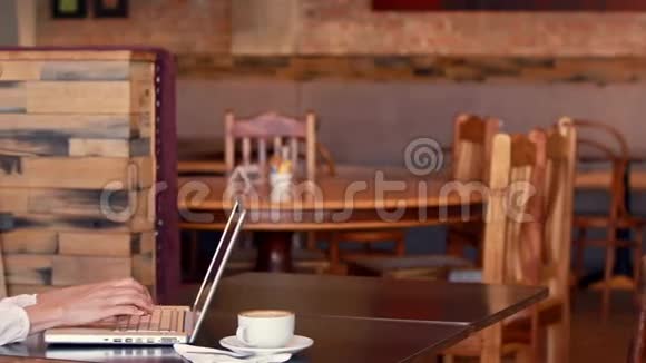 漂亮女人一边喝咖啡一边用笔记本电脑视频的预览图