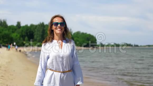 快乐微笑的女人漫步在夏日海滩视频的预览图