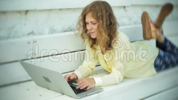 美丽的女人在公园的木凳上用笔记本电脑工作视频的预览图