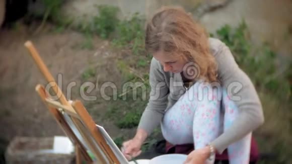 年轻女子在画架上画画刷旧旧桥视频的预览图