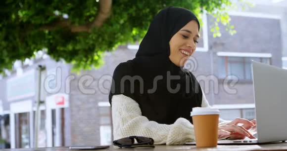 戴头巾的女人在笔记本电脑上工作视频的预览图