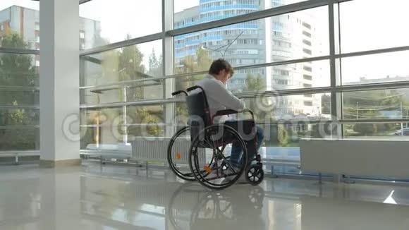轮椅上的残疾商人在窗口使用智能手机视频的预览图