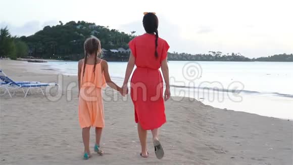 年轻漂亮的妈妈和她可爱的小女儿在热带海滩玩得很开心视频的预览图