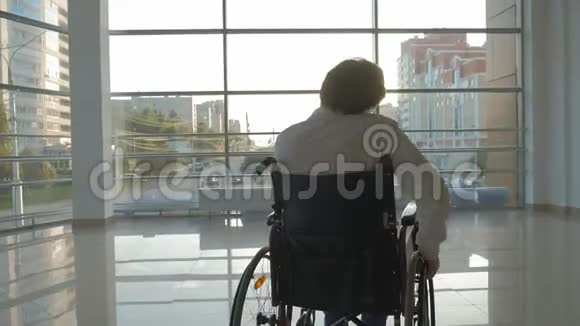 轮椅上的残疾商人在窗口使用智能手机视频的预览图