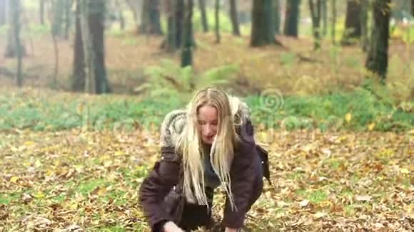 美丽的女人微笑着在公园里扔树叶视频的预览图