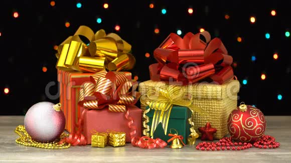 漂亮的圣诞礼物盒和装饰在木地板上在黑色背景上五颜六色的闪光花环上视频的预览图