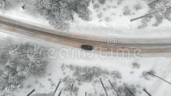 雪林中的冬季乡村道路无人驾驶飞机鸟瞰视频的预览图