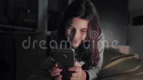 十几岁的女孩网上购物在床上看智能手机一个小女孩写了一条信息视频的预览图