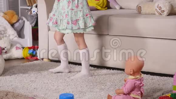 快乐的金发女孩穿着裙子在家里或幼儿园的一间阳光明媚的白色房间里在室内尽情跳舞视频的预览图