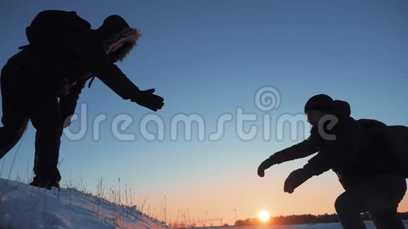 团队合作商务旅行剪影概念两个徒步旅行者冬季雪游客登山到山顶视频的预览图