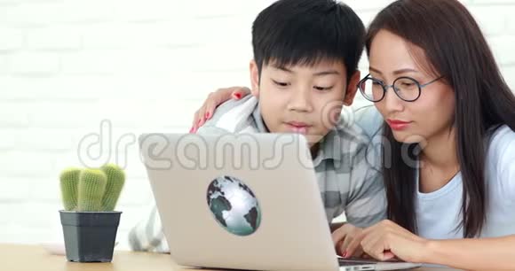 快乐的亚洲家庭母亲和儿子一边看着电脑笔记本一边笑视频的预览图
