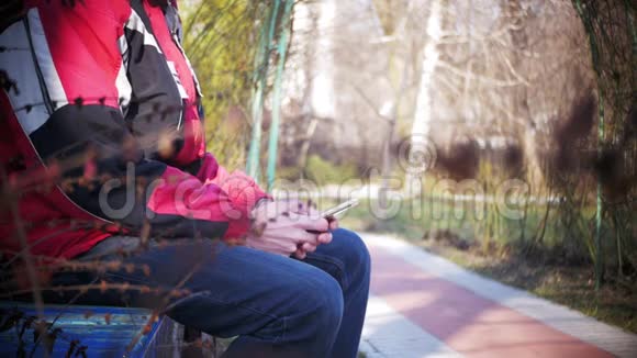 在城市公园的长椅上使用手机的年轻人视频的预览图