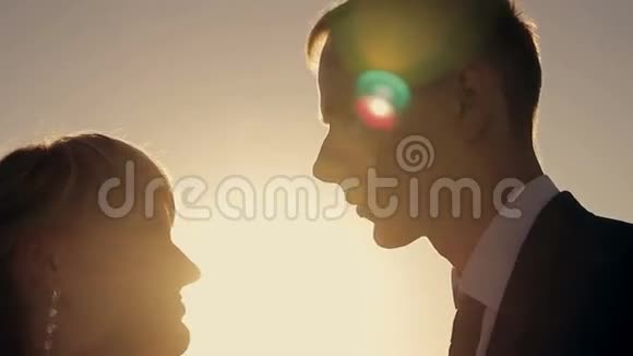 在夕阳下亲吻一对年轻夫妇的剪影视频的预览图