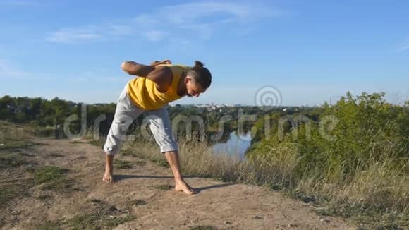 年轻的运动男子站在瑜伽姿势户外在大自然中练习瑜伽动作和姿势的白人美丽美丽视频的预览图