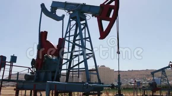 阿塞拜疆巴库一个油田的油泵蓝天背景下的油泵工作剪影视频的预览图