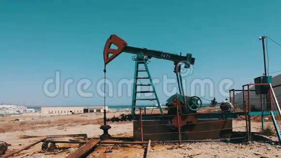 工作油泵和一个旧生锈的铁桶附近的蓝天和云彩的背景工作油中的油泵视频的预览图