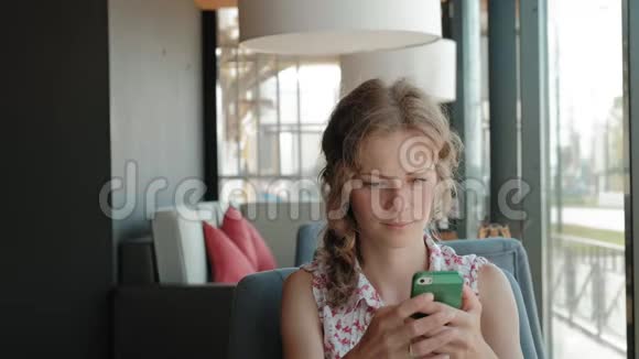 漂亮的女人在咖啡馆里使用智能手机视频的预览图
