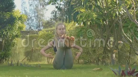 一个年轻女孩在自家后院做的体式瑜伽表演视频的预览图