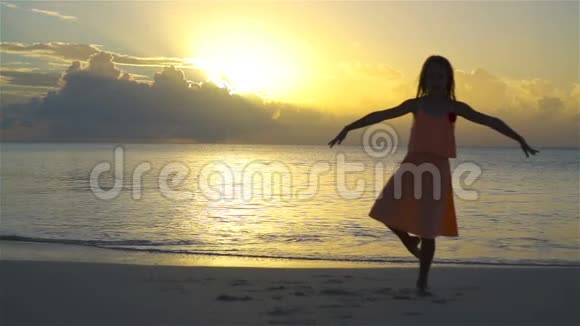 日落时分在白色海滩上可爱的小女孩剪影流动人口视频的预览图